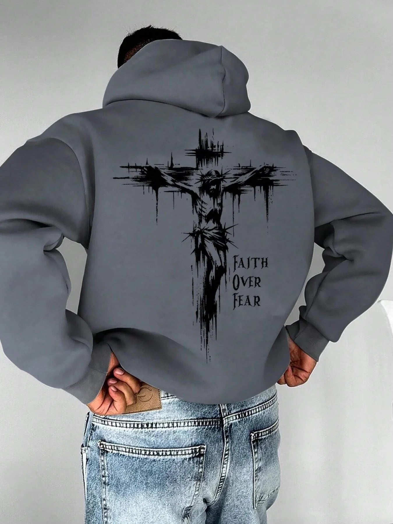 A men's hoodie with the words "Christian faith Overcomes fear" printed on it features a cross-shaped design on the back